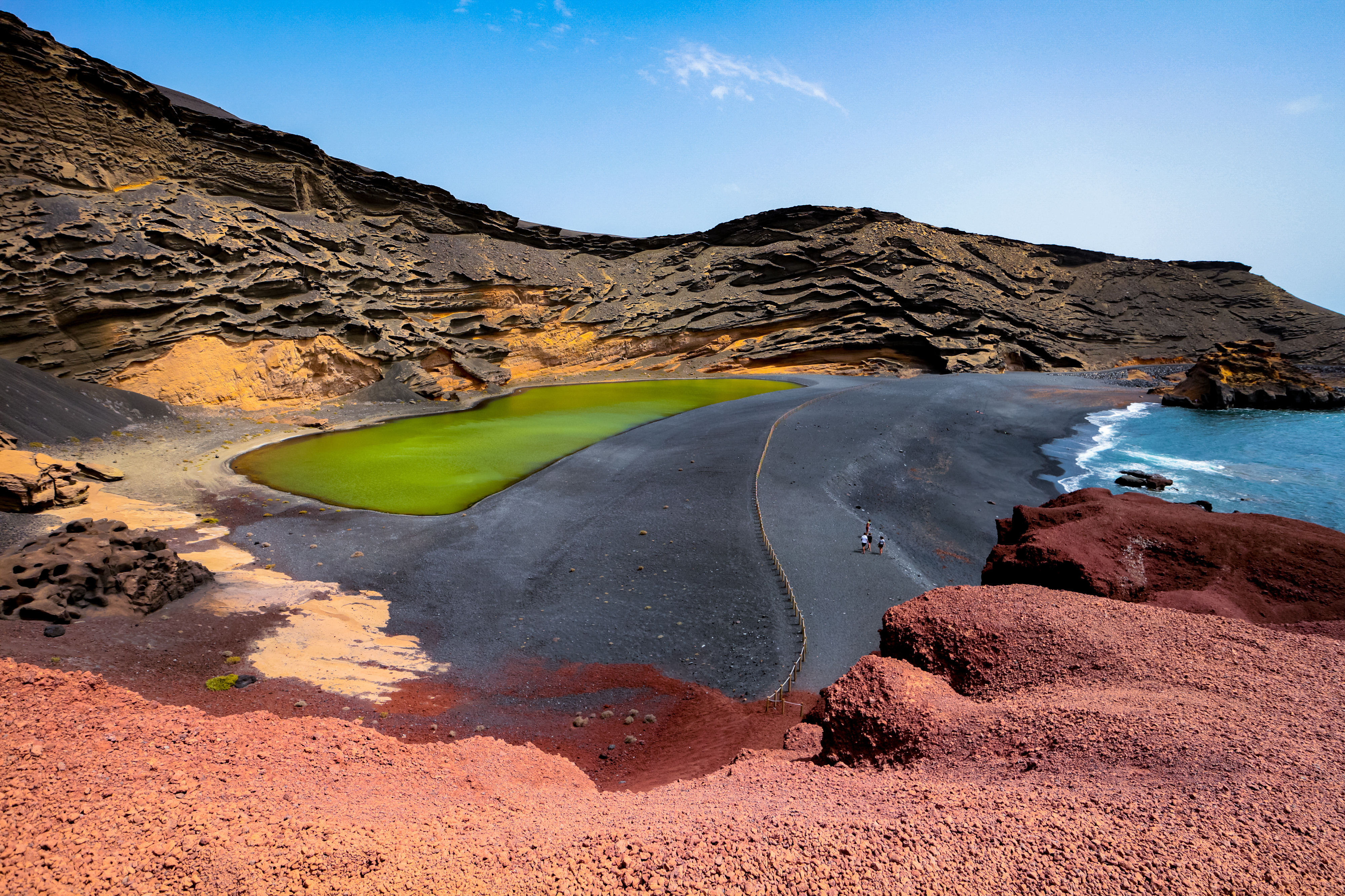 Lago Verde ("Green Lake") or Charco de Los Clicos in El Golfo, Lanzarote, Canary Islands, Spain. Uniquely colorful landscape with black sand beach, dark volcanic rocks and red earth.